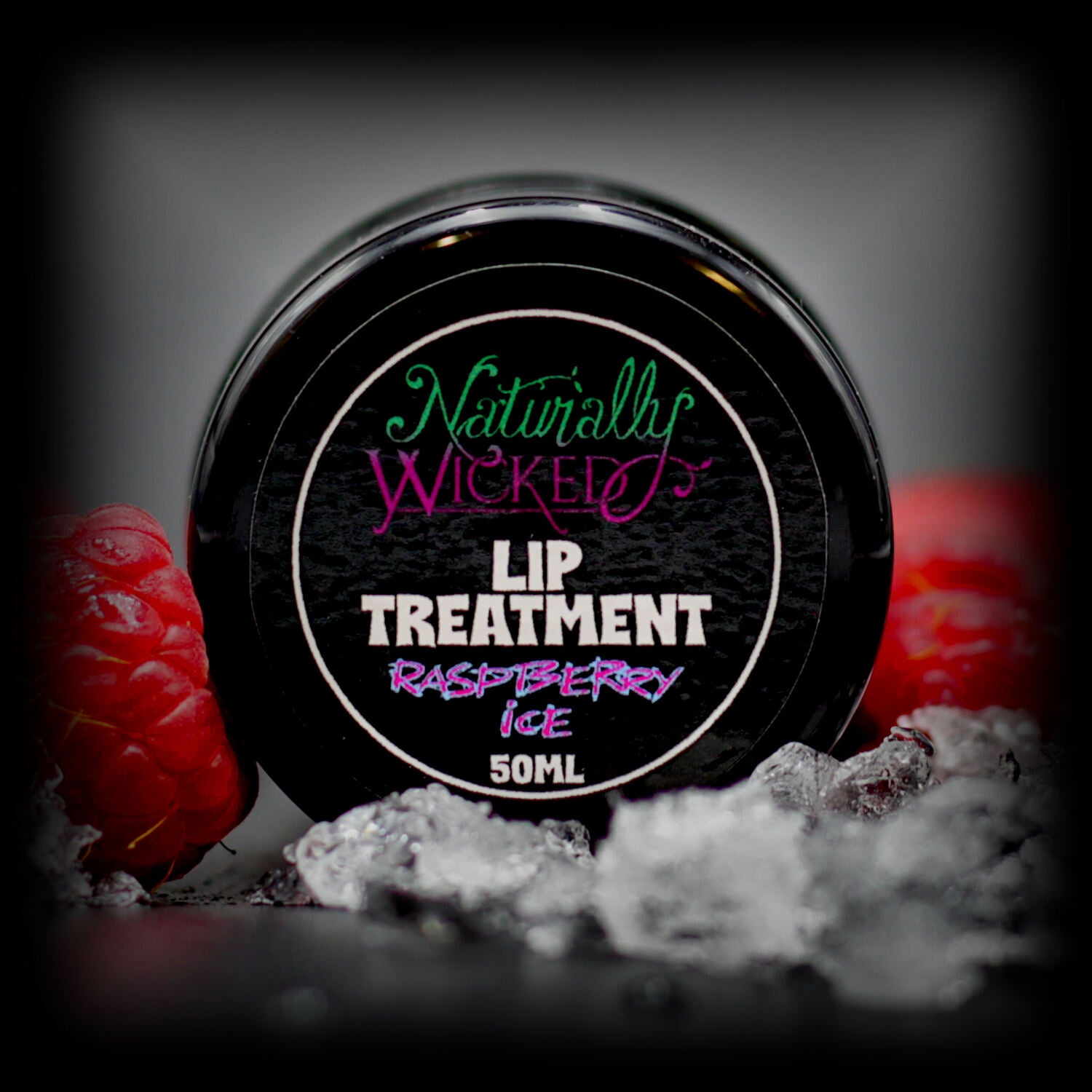 Naturally Wicked Raspberry Ice Lip Treatment Lid With Two Bright Red Raspberries & Ice In Front